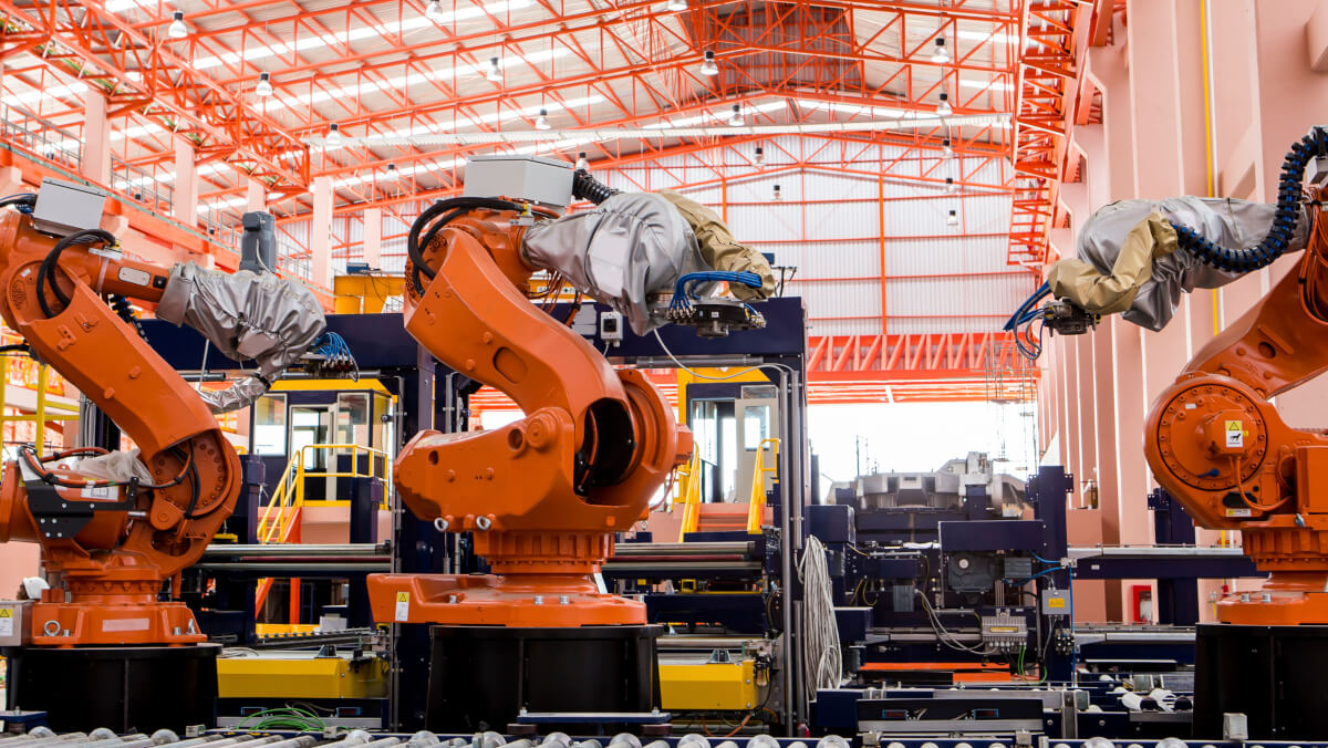 orange robotic arms inside a factory