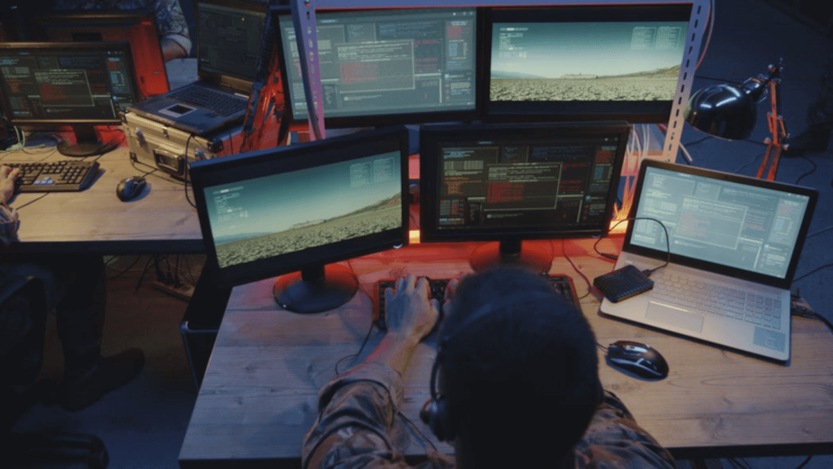 person sits at workstation with many screens
