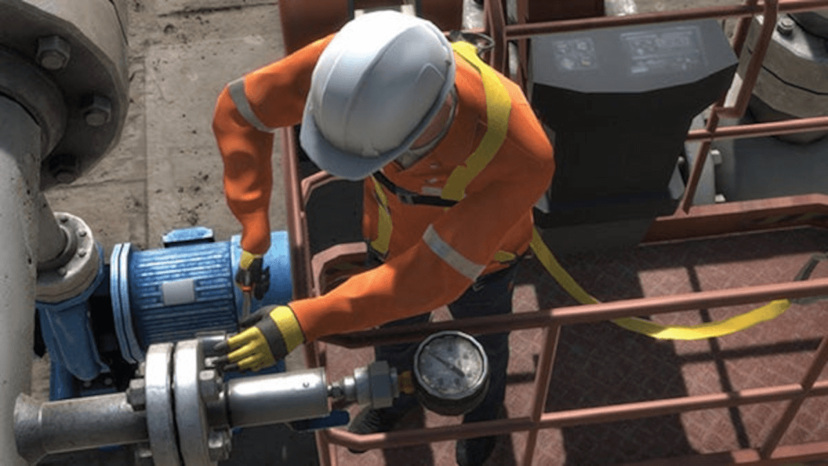 man wearing hard hat works on pipes